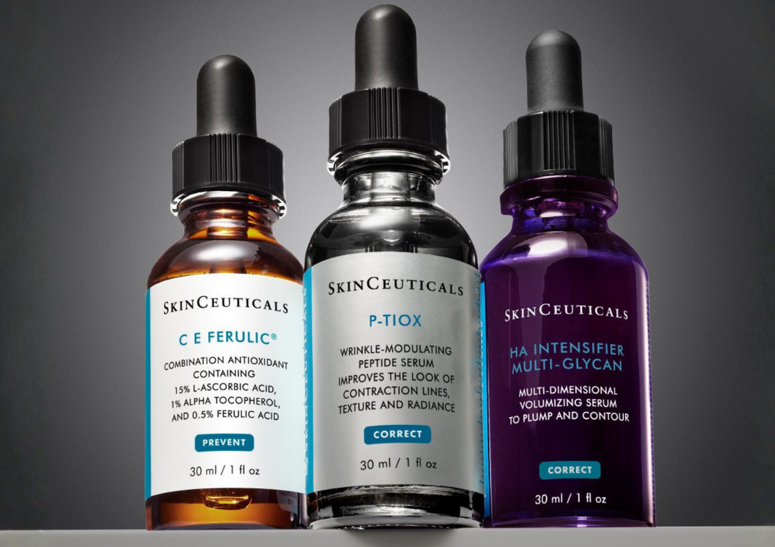Three SkinCeuticals serum bottles with dropper tops arranged in a row on a dark background.